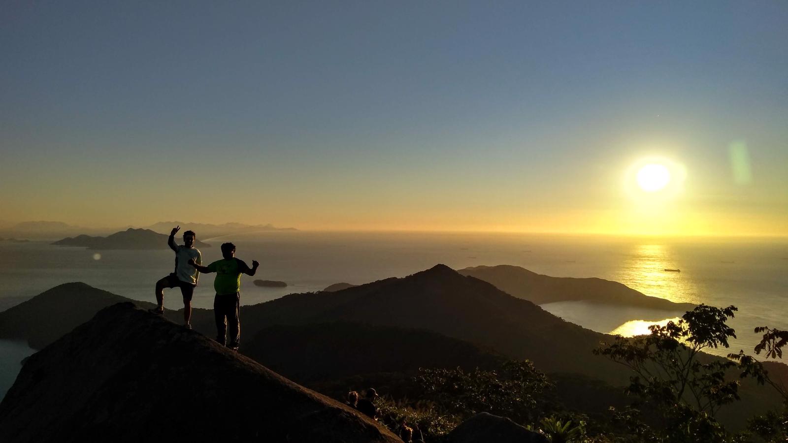 Hikers watching the sunset from a mountain trail on Ilha Grande