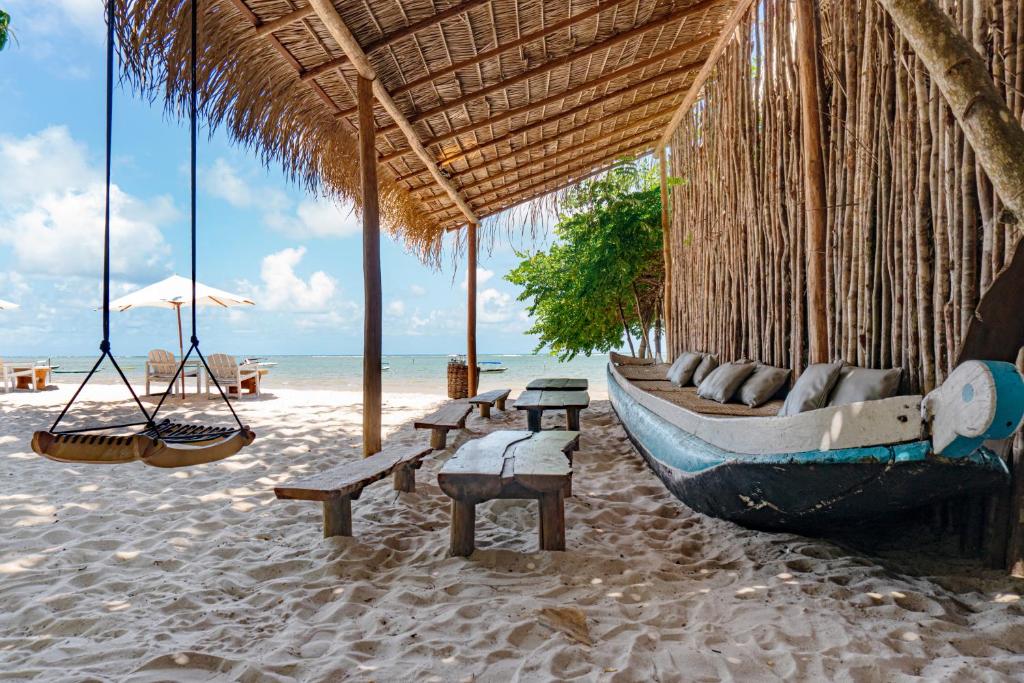 Thatched beach bar with hammocks and a wooden boat in Moreré, Boipeba