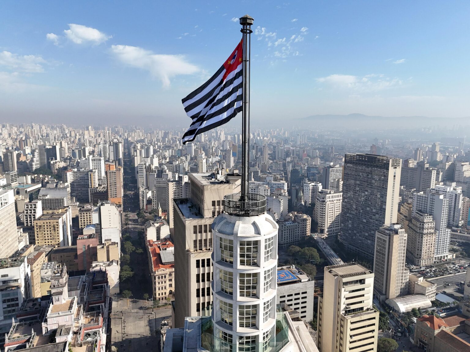 São Paulo skyline stretching to the horizon, with the São Paulo state flag in the foreground