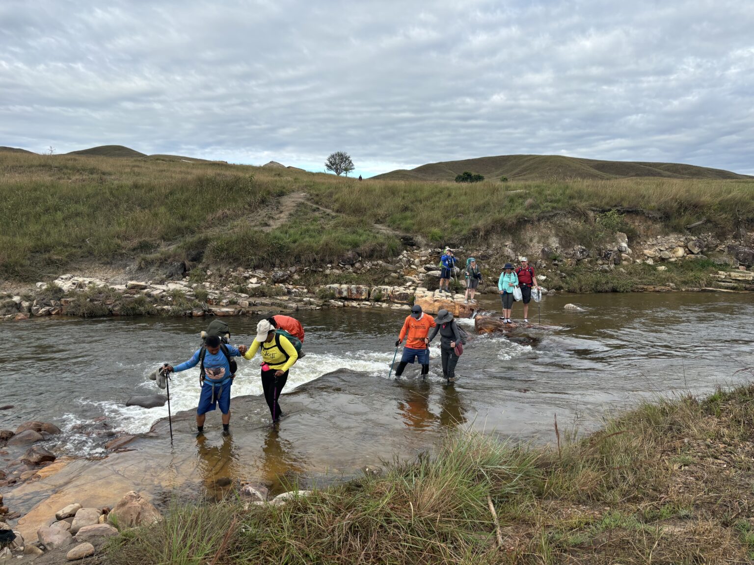 Trekkers crossing a shallow river on the trail to Mount Roraima